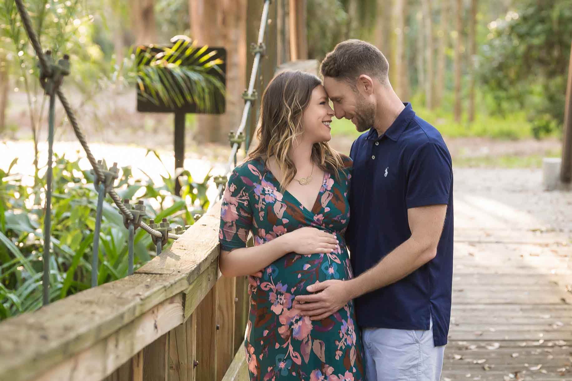 Pregnant woman gazing into husband's eyes at a park on a bridge