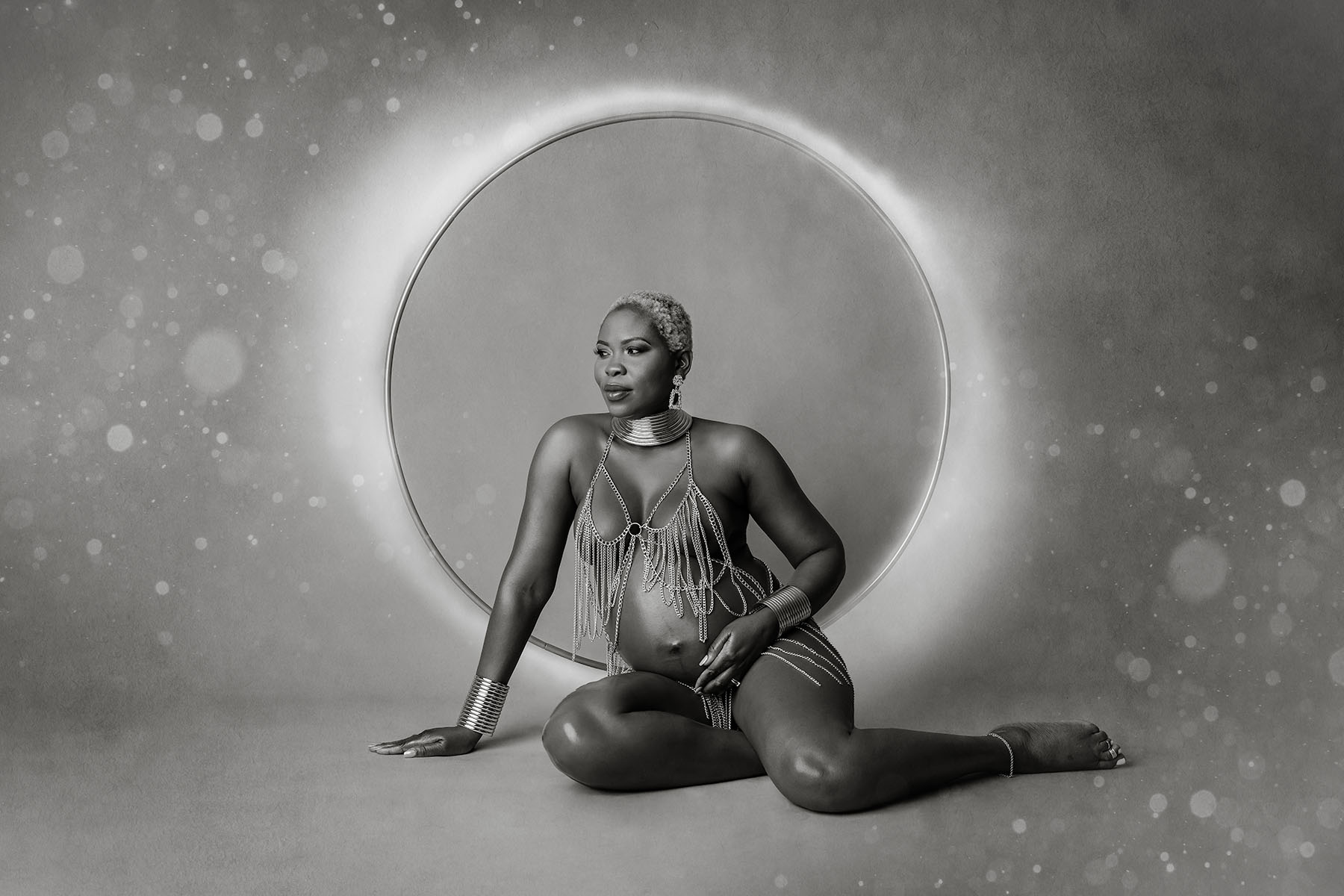 Artistic black & white image of a nude pregnant woman sitting on the floor.