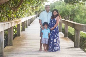A pregnant woman, her husband and her son are posed on the boardwalk, surrounded by sea oats at Jetty Park near Merritt Island Florida.