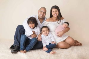 A family of 5 is sitting posed for a portrait during a photo shoot.