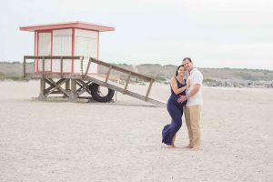 Pregnant couple posed in front of a life guard stand on the beach in Brevard County Florida.