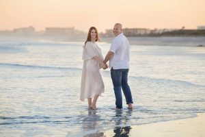 Pregnant couple standing in the surf at Jetty Park in Florida.
