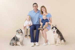 Family Portrait of a mom, dad & 2 boys sitting with their dogs by their side